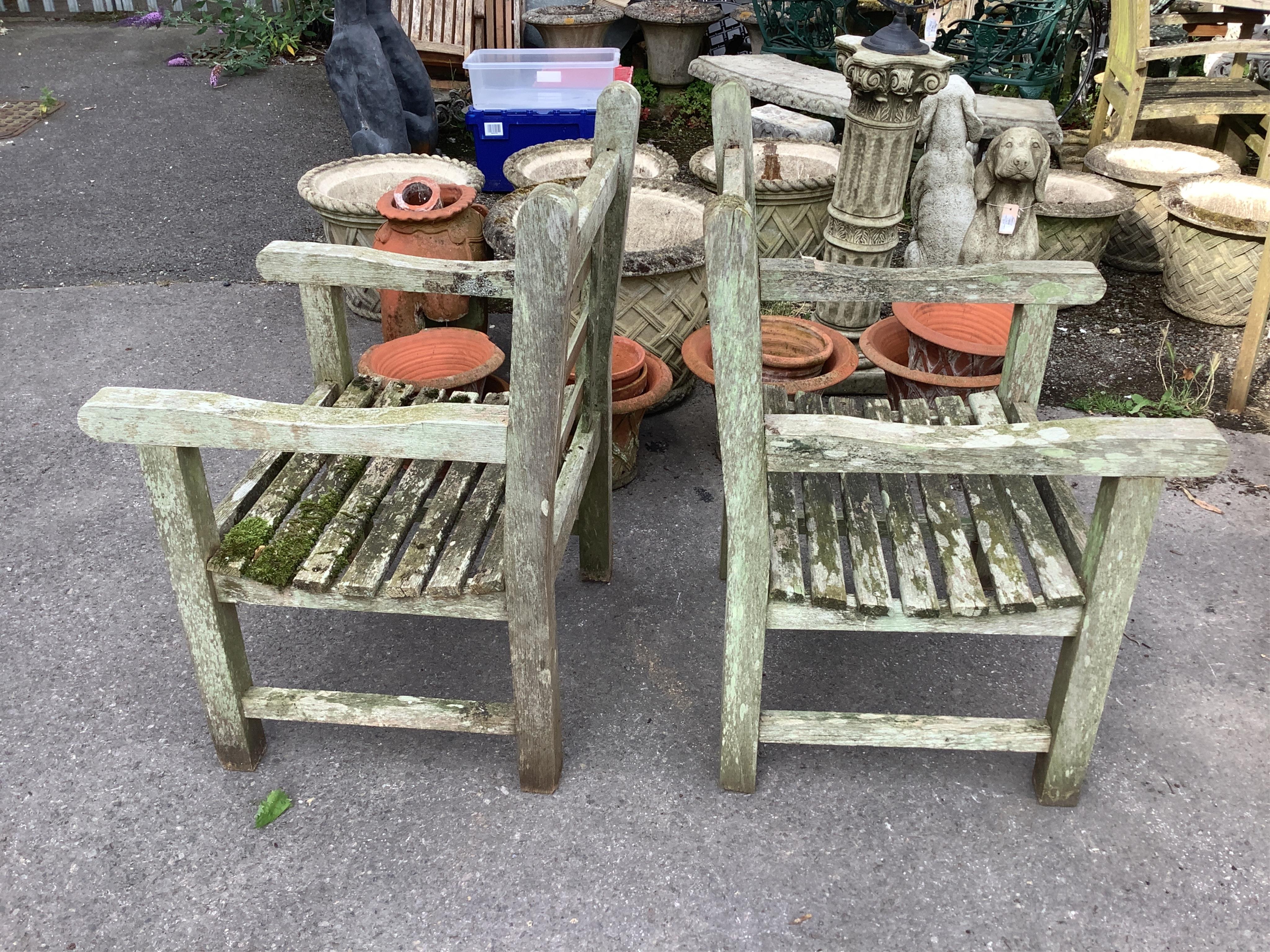 A pair of weathered teak garden armchairs, width 63cm, depth 64cm, height 94cm. Condition - fair